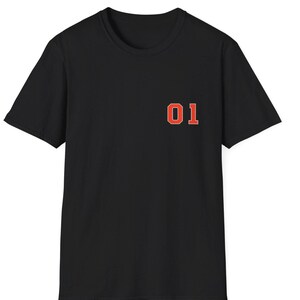 May include: A black short-sleeved t-shirt featuring the number 01 printed on the left chest in a bold orange font with a thin white outline. The garment has a classic crew neckline and a straight hem, providing a simple and clean design.