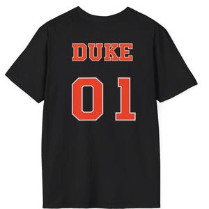 May include: A black short-sleeve t-shirt featuring the word DUKE in orange block letters above the large orange number 01, both outlined in white, centered on the back of the garment.