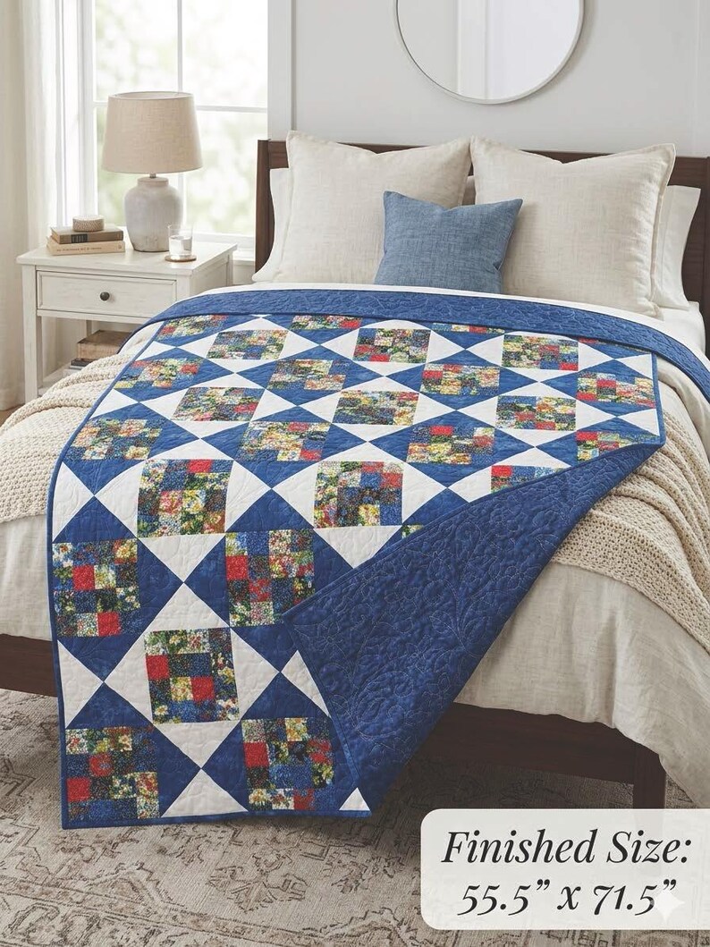 May include: A blue and white quilt with a patchwork design, featuring squares of floral fabric. The quilt is draped over a bed, showcasing its diamond pattern. Finished size is 55.5" x 71.5".