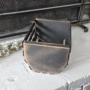Peut inclure: Un pot de fleurs en bois noir vieilli. Le pot a une forme rectangulaire avec des côtés inclinés et une bordure de couleur naturelle. Il est conçu pour contenir des plantes et ajoute une touche rustique à tout espace.