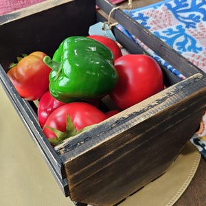 Peut inclure: Une caisse en bois rustique remplie de tomates rouges vives et d'un poivron vert. La caisse a une finition brun foncé vieillie, suggérant une esthétique vintage ou de ferme. Les légumes sont disposés à l'intérieur, créant un affichage coloré.