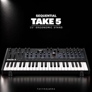 May include: A black Sequential Take 5 synthesizer resting on a 15° ergonomic stand. The keyboard features black and white keys, numerous control knobs, and sliders. Text above reads: SEQUENTIAL TAKE 5 15° ERGONOMIC STAND. Text below reads: fatlikejabba.