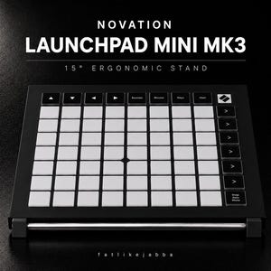 Könnte beinhalten: Ein schwarzer, ergonomischer 15-Grad-Ständer für den Novation Launchpad Mini MK3 MIDI-Controller. Der Ständer verfügt über einen eleganten schwarzen Rahmen mit einer horizontalen Stützstange aus silbernem Metall an der Basis.