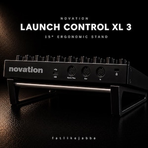 Könnte beinhalten: Schwarzer Novation Launch Control XL 3 MIDI-Controller auf einem 15-Grad-Ergonomieständer. Der Controller hat mehrere Knöpfe und Tasten mit USB- und MIDI-Anschlüssen. Der Ständer ist schwarz mit einer silbernen Stange.