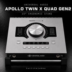 Könnte beinhalten: Ein silbernes Universal Audio Apollo Twin X Quad Gen2 Audio-Interface auf einem 15-Grad-Ergonomieständer. Das Gerät verfügt über einen großen silbernen Drehregler, mehrere Tasten, LED-Pegelanzeigen und den Text 'apollo twin | x' oben.