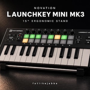 May include: A black Novation Launchkey Mini MK3 MIDI keyboard with a 15-degree ergonomic stand. The keyboard features black and white keys, illuminated pads, and control knobs. The text "LAUNCHKEY MINI MK3" is displayed at the top.