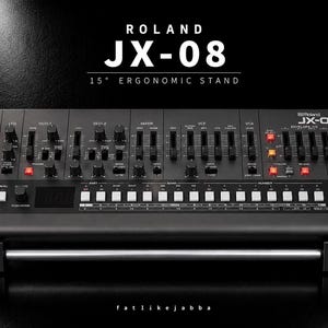 Könnte beinhalten: Ein schwarzes Roland JX-08 Synthesizer-Modul auf einem ergonomischen 15-Grad-Ständer. Das Gerät verfügt über zahlreiche schwarze Schieberegler, Drehknöpfe und bunte quadratische Tasten, mit dem Text ROLAND JX-08 15° ERGONOMIC STAND darüber.