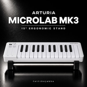 Peut inclure: Un clavier MIDI Arturia MicroLab MK3 blanc avec des touches noires et blanches, placé sur un support ergonomique à 15 degrés. Le texte ARTURIA MICROLAB MK3 15° ERGONOMIC STAND est affiché au-dessus du clavier sur un fond noir.