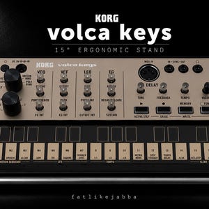 Può includere: Un sintetizzatore analogico Korg Volca Keys montato su un supporto ergonomico nero inclinato di 15 gradi. Il dispositivo presenta un pannello di controllo beige con manopole, pulsanti ed etichette nere, incluse le sezioni VCO, VCF, LFO, EG e Delay.