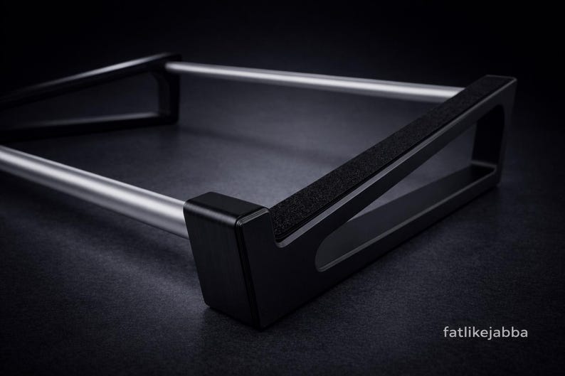 Puede incluir: Un soporte de metal negro y plateado con dos barras cil&iacute;ndricas plateadas paralelas conectadas por dos marcos laterales triangulares negros con bordes superiores texturizados. El texto fatlikejabba est&aacute; impreso en blanco abajo a la derecha.
