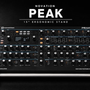 May include: A black Novation Peak eight-voice polyphonic synthesizer with wood side panels, mounted on a 15-degree ergonomic stand. The control panel features numerous knobs, sliders, buttons, and a digital display screen with text labels.