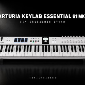 May include: A white Arturia Keylab Essential 61 MK3 MIDI keyboard controller with black and white keys, backlit pads, knobs, faders, and a central display screen. The text ARTURIA KEYLAB ESSENTIAL 61 MK3 15° ERGONOMIC STAND and fatlikejabba are visible.
