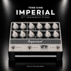 Op de afbeelding: Een zwart en zilverkleurig Tone King Imperial 15 degree ergonomic stand gitaarpedaal met twaalf witte bedieningsknoppen, een metalen rooster en drie zilveren voetschakelaars gelabeld Tremolo, Channel en Bypass, inclusief de tekst Tri Tube Preamp.