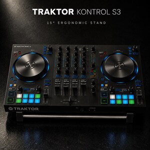 Könnte beinhalten: Schwarzer Traktor Kontrol S3 DJ-Controller mit silbernen Jogwheels und beleuchteten blauen und grünen Tasten. Der Text "TRAKTOR KONTROL S3" und "15° ERGONOMIC STAND" ist oben angezeigt.
