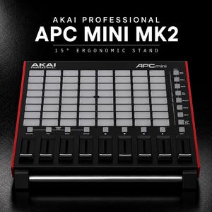 Może przedstawiać: Kontroler Akai Professional APC Mini MK2 z ergonomiczną podstawką 15 stopni. Czarne urządzenie posiada siatkę jasnoszarych padów, dziewięć czarnych suwaków i różne przyciski sterujące. Tekst na urządzeniu zawiera Akai Professional oraz APC mini.