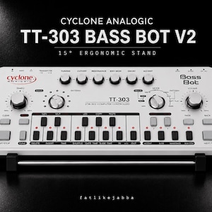 May include: A white Cyclone Analogic TT-303 Bass Bot V2 synthesiser on a 15-degree ergonomic stand. The device features black knobs, a small keyboard with black and grey buttons, and printed text including "TT-303" and "Bass Bot" on the top surface.