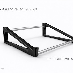 Pode incluir: Suporte ergonómico preto para teclados AKAI MPK Mini mk3. O suporte tem um ângulo de 15 graus e duas barras prateadas que conectam os suportes pretos. O texto "AKAI MPK Mini mk3" e "15° ERGONOMIC STAND" são visíveis.