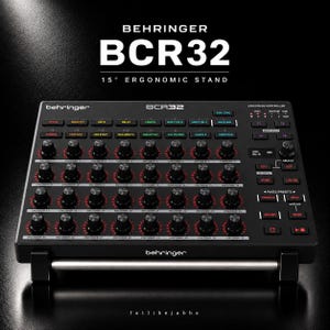 Puede incluir: Un controlador MIDI Behringer BCR32 negro con treinta y dos codificadores rotativos con anillos rojos, numerosos botones retroiluminados y un soporte ergonómico de 15 grados. El dispositivo muestra el texto Behringer BCR32 y 15-degree ergonomic stand.