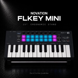 Peut inclure: Un clavier contrôleur MIDI Novation FLkey Mini noir posé sur un support ergonomique à 15 degrés. L'appareil présente des touches blanches et noires, une rangée de pads rétroéclairés bleus et violets, des boutons de contrôle et des touches.