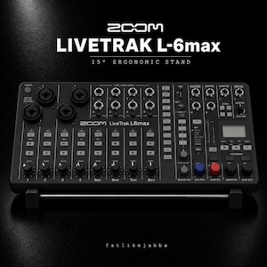 Könnte beinhalten: Ein schwarzer Zoom LiveTrak L-6max Digitalmixer und Recorder mit mehreren XLR-Eingängen, Kanalfadern, Drehreglern und einem kleinen Display. Das Gerät ist auf einem 15-Grad-ergonomischen Ständer montiert und verfügt über beschriftete Bedienelemente.