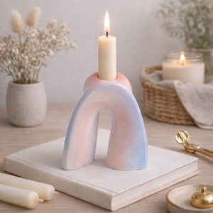 May include: A white ceramic mug with a black handle and the text "But First, Coffee" in a bold, black font. The mug is set against a blurred background, suggesting a cozy setting.