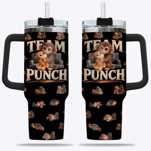 May include: Two black insulated tumblers with handles, decorated with cartoon monkeys and the text "TEAM PUNCH." Each tumbler has a silver lid, a black handle, and a straw. The tumblers are designed for cold beverages.