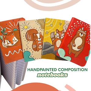 Puede incluir: Cuatro cuadernos de composición pintados a mano con ilustraciones de animales. Los cuadernos presentan un diseño de zorro, ardilla y oso. Los cuadernos son de color naranja, beige y rojo con páginas rayadas blancas. El texto "HANDPAINTED COMPOSITION notebooks" está en la parte inferior.