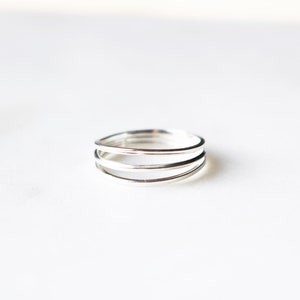May include: A silver ring with three bands that are intertwined.
