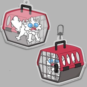 Pode incluir: Dois porta-chaves de acr&iacute;lico com um gato branco de desenho animado com grandes olhos azuis dentro de uma caixa de transporte vermelha e cinzenta. Um mostra o gato na caixa aberta, o outro mostra o gato na caixa fechada.