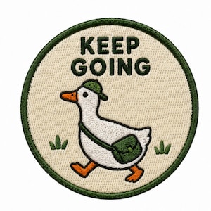 Könnte beinhalten: Ein runder Stickaufnäher mit cremefarbenem Hintergrund und dunkelgrünem Rand. Er zeigt eine weiße Ente mit grüner Kappe und grüner Umhängetasche. Der Text KEEP GOING ist in Dunkelgrün über der Ente gestickt, ergänzt durch kleine grüne Grasbüschel.
