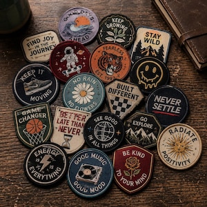 May include: A collection of various embroidered fabric patches featuring diverse designs, including an astronaut, a tiger, a basketball, a record player, a rose, and motivational text such as "Keep Growing," "Stay Wild," and "Radiate Positivity."