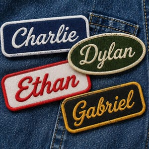 May include: Four rectangular and oval embroidered patches with white, red, and yellow cursive lettering. The patches feature the names Charlie in white on navy blue, Dylan in white on olive green, Ethan in red on white, and Gabriel in yellow on black.