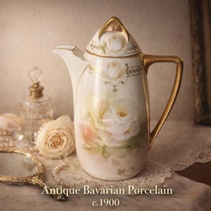 May include: Antique Bavarian porcelain coffee pot, c.1900, with a floral design in soft pinks and yellows. The pot has a gold handle and trim, and is displayed with a hand mirror, pearls, and perfume bottles.