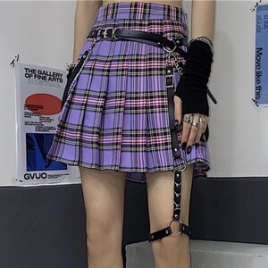 Pleated Mini Skirt | Casual Ruffle Plaid Fashion | Streetwear Grunge Outfit

Woman wearing a layered pleated mini skirt with plaid design and ruffle details, styled in a grunge Y2K streetwear outfit.