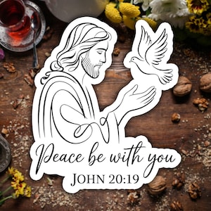 May include: A white sticker featuring a black line drawing of a religious figure with long hair and a beard, holding a dove. The text "Peace be with you" and "JOHN 20:19" are below the image.