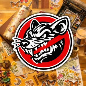 May include: A circular sticker featuring a black and white illustration of a snarling wolf's head with a red prohibition symbol over it. The sticker is surrounded by other decorative items, including a tumbler, stickers, and a vintage typewriter.
