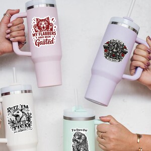 Puede incluir: Cuatro vasos aislados en varios colores, cada uno con una pegatina gr&aacute;fica. Las pegatinas presentan texto e ilustraciones, incluyendo un gato, un levantador de pesas y un oso. Los vasos tienen asas y pajitas.
