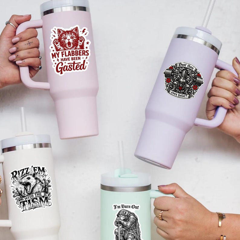 Puede incluir: Cuatro vasos aislados en varios colores, cada uno con una pegatina gr&aacute;fica. Las pegatinas presentan texto e ilustraciones, incluyendo un gato, un levantador de pesas y un oso. Los vasos tienen asas y pajitas.