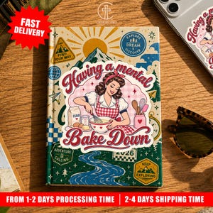 May include: A hardcover journal featuring a retro-style illustration of a person in a red checkered apron mixing ingredients in a bowl. The text reads Having a mental Bake Down. The cover includes mountain, sun, and river graphics with adventure-themed icons.