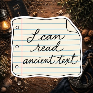 May include: A die-cut sticker shaped like a piece of lined notebook paper with three binder holes on the left side. The sticker features the black cursive text "I can read ancient text" printed across the center on a light cream background.