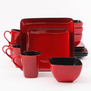 May include: A red square dinnerware set with black trim. The set includes square plates, bowls, and mugs. The mugs have heart-shaped handles. The interior of the mugs and bowls are black.