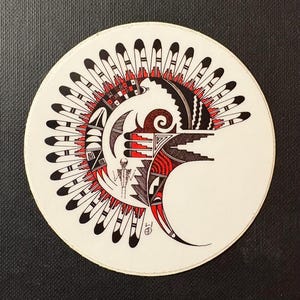 Puede incluir: Un diseño circular con un motivo de inspiración nativa americana. La obra de arte utiliza colores negro, rojo y blanco. El diseño incluye plumas, formas geométricas y una figura humana estilizada. El fondo es negro.