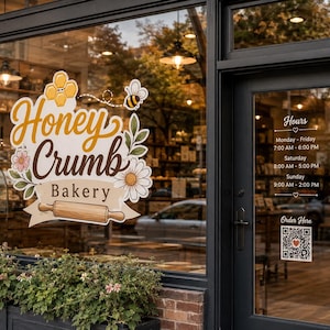 May include: A storefront window decal for Honey Crumb Bakery featuring a yellow honeycomb, a bee, flowers, and a wooden rolling pin. The glass door displays business hours from Monday to Sunday and a QR code labeled Order Here.