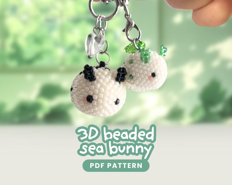 May include: Two 3D beaded sea bunny charms crafted from small white beads. One features black accents and the other green accents, both with tiny black eyes and pink cheeks. They hang from silver-toned metal clasps. Text reads 3D beaded sea bunny PDF PATTERN.