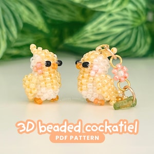 以下が含まれることがあります： 黄色、白、ピンクの小さなビーズで作られた3Dビーズのオカメインコのフィギュア2体。黒いビーズの目とオレンジ色のアクセントが特徴です。1体は独立したオーナメントで、もう1体は小さな花のチャームが付いたゴールドトーンの金属リングに取り付けられています。