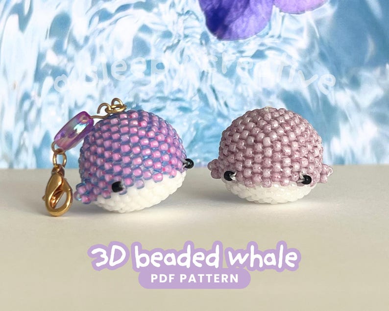 May include: Two beaded whale figurines. One whale is purple and white with a gold clasp and charm. The other whale is purple and white. The text "3D beaded whale PDF pattern" is at the bottom of the image.