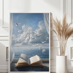 以下が含まれることがあります： カモメ、ヨット、雲の多い空が描かれた海の風景の額入りアートプリント。開いた本が前景にあります。アートワークは白いフレームに入っています。