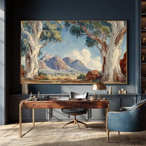 May include: A large landscape painting featuring a mountain range and two large trees framing the view. The artwork has a gold frame and is displayed above a wooden desk with a brass lamp. The room has a blue color scheme.