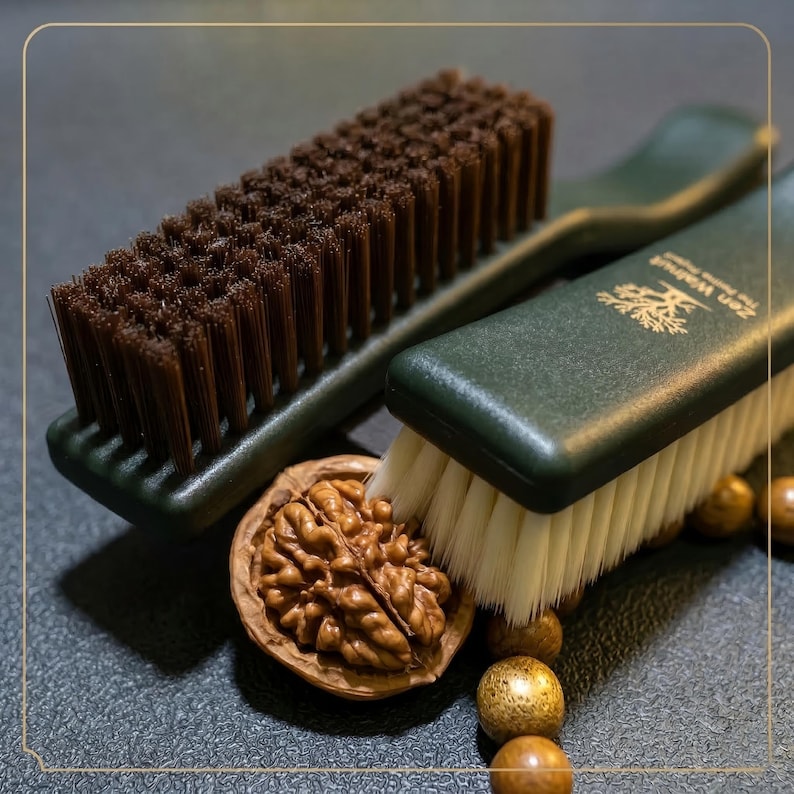 K&ouml;nnte beinhalten: Zwei gr&uuml;n-griffige B&uuml;rsten mit braunen und wei&szlig;en Borsten werden mit einer Walnuss und Holzperlen gezeigt. Auf den B&uuml;rsten steht "Zen Walnut". Die Borsten sind dicht gepackt, und die Walnuss ist ge&ouml;ffnet und zeigt das Nussfleisch.