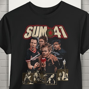 Op de afbeelding: Een zwart t-shirt met een grafische print van de band Sum 41. Het ontwerp bevat de tekst "Sum 41" in een vetgedrukt lettertype met een rode ster, een centrale afbeelding van de bandleden en vier kleinere vierkante panelen eronder.